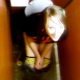 A girl video-records her friend finishing up her poop in a public restroom. In her American, southern accent, she asks us if we want to see her poop. When she stands up, we can see a few floaters mixed in with the toilet paper.
